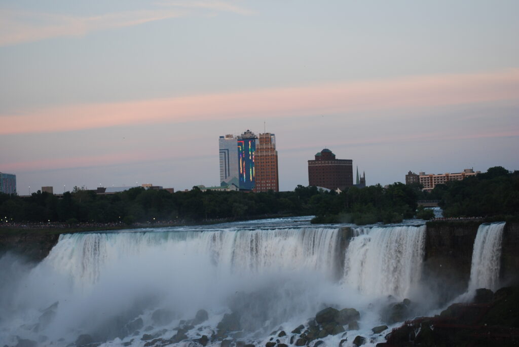 The American Falls at dusk with the downtown Niagara Falls, New York skyline behind it