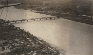 Black-and-white 1920 aerial photograph of Bridgeburg, Ontario (now part of Fort Erie), showing the steel International Railway Bridge spanning the wide Niagara River, with the town's streets and buildings lining the far bank and tree-shaded homes in the foreground.