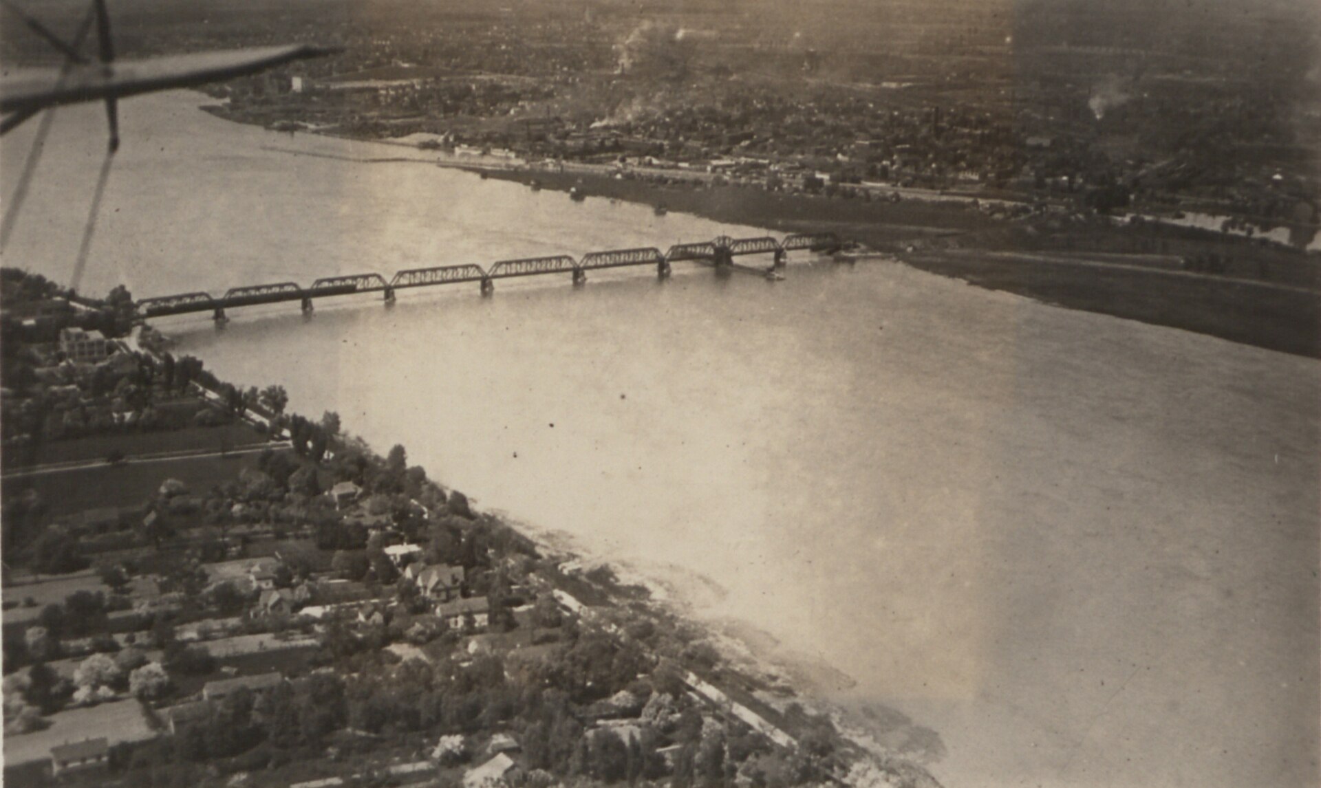 Black-and-white 1920 aerial photograph of Bridgeburg, Ontario (now part of Fort Erie), showing the steel International Railway Bridge spanning the wide Niagara River, with the town's streets and buildings lining the far bank and tree-shaded homes in the foreground.