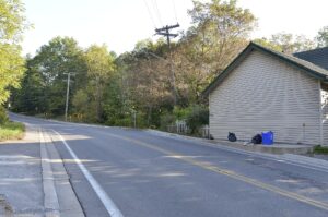 A quiet rural two-lane road, Effingham Street, curving north through green forested hills in the hamlet of Effingham, Pelham, Ontario.