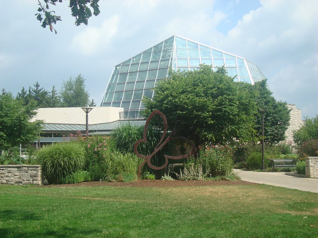 The curved glass dome of the Butterfly Conservatory building surrounded by lawn and trees